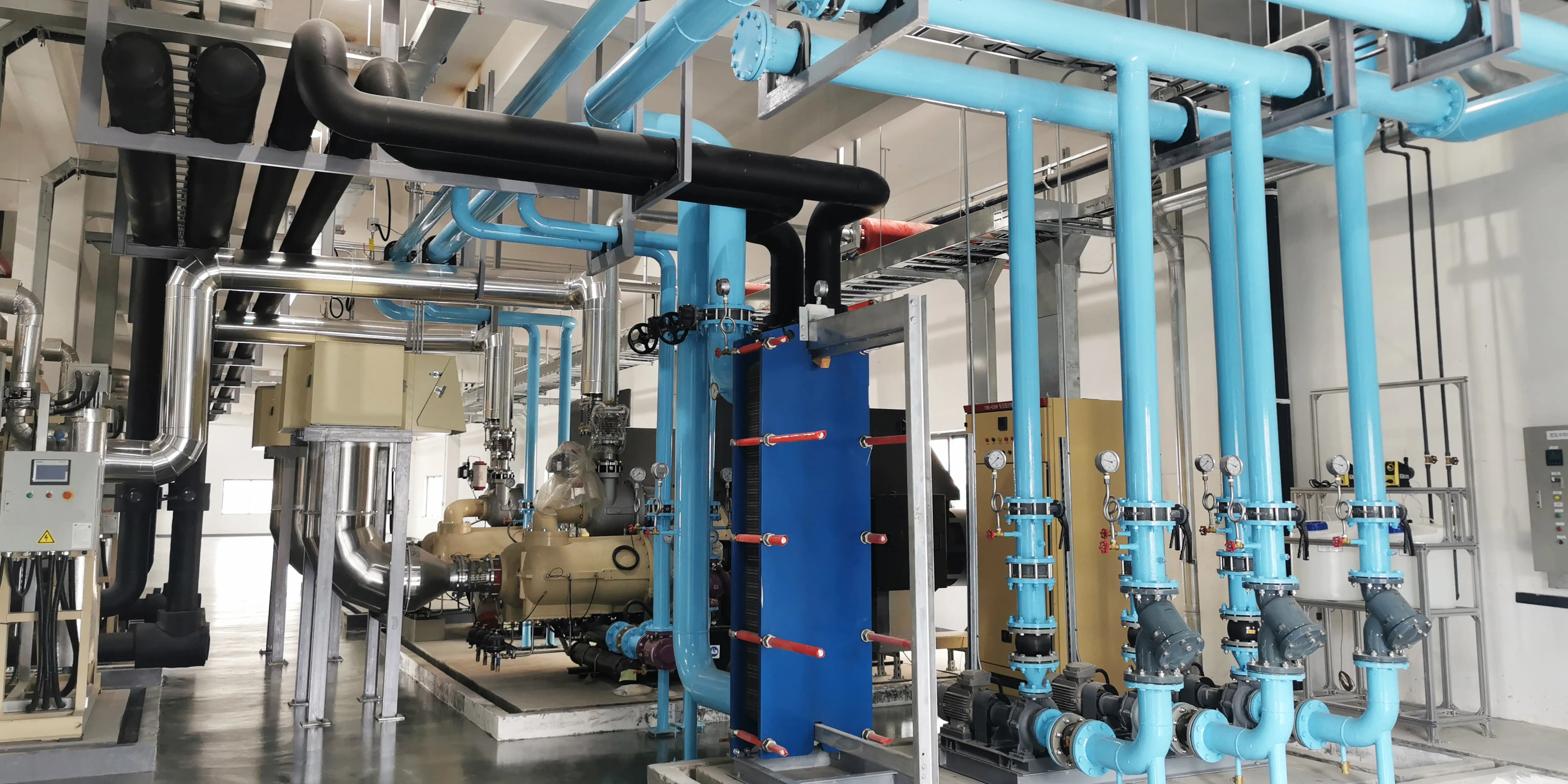 Industrial water chiller unit installed in a factory, showing multi-stage cooling system with compressors, evaporators, and control panel.